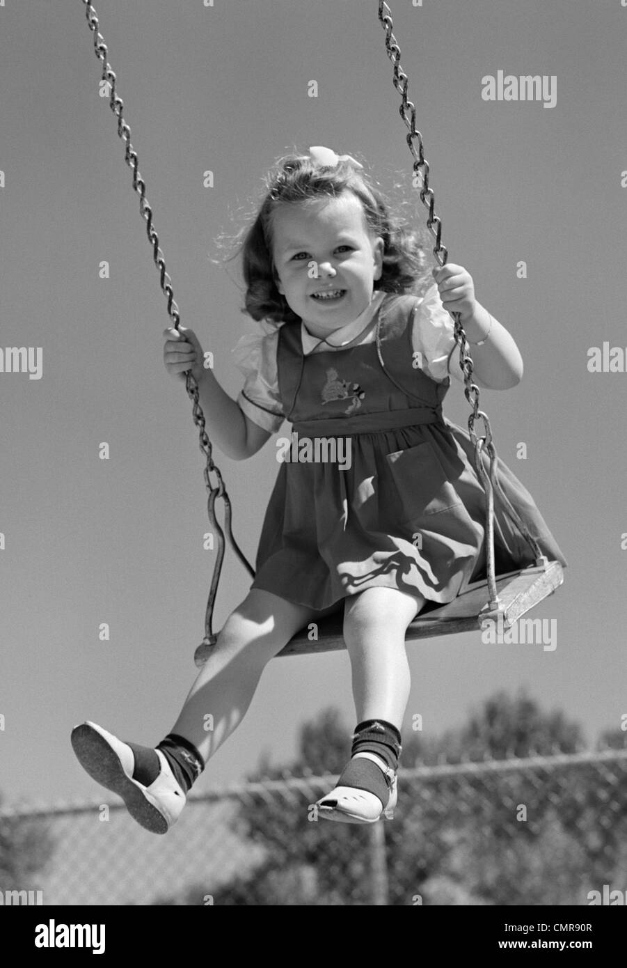1940s sorridente ragazza basculante in parco giochi SWING Foto Stock
