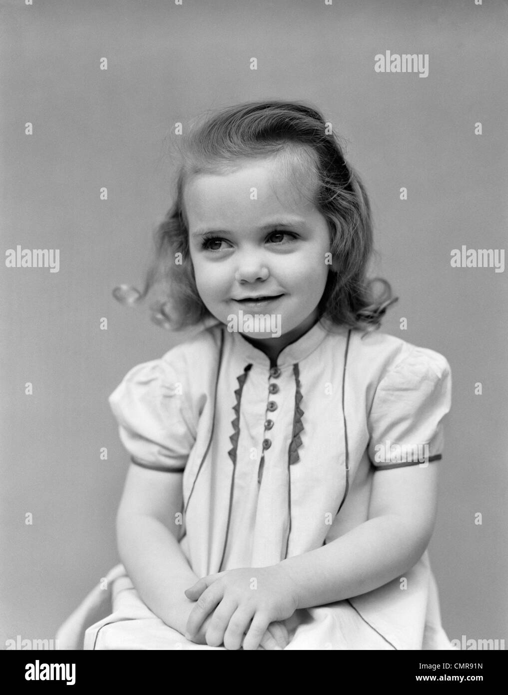 1930s bambino bambina in posa seduta con le mani insieme Foto Stock
