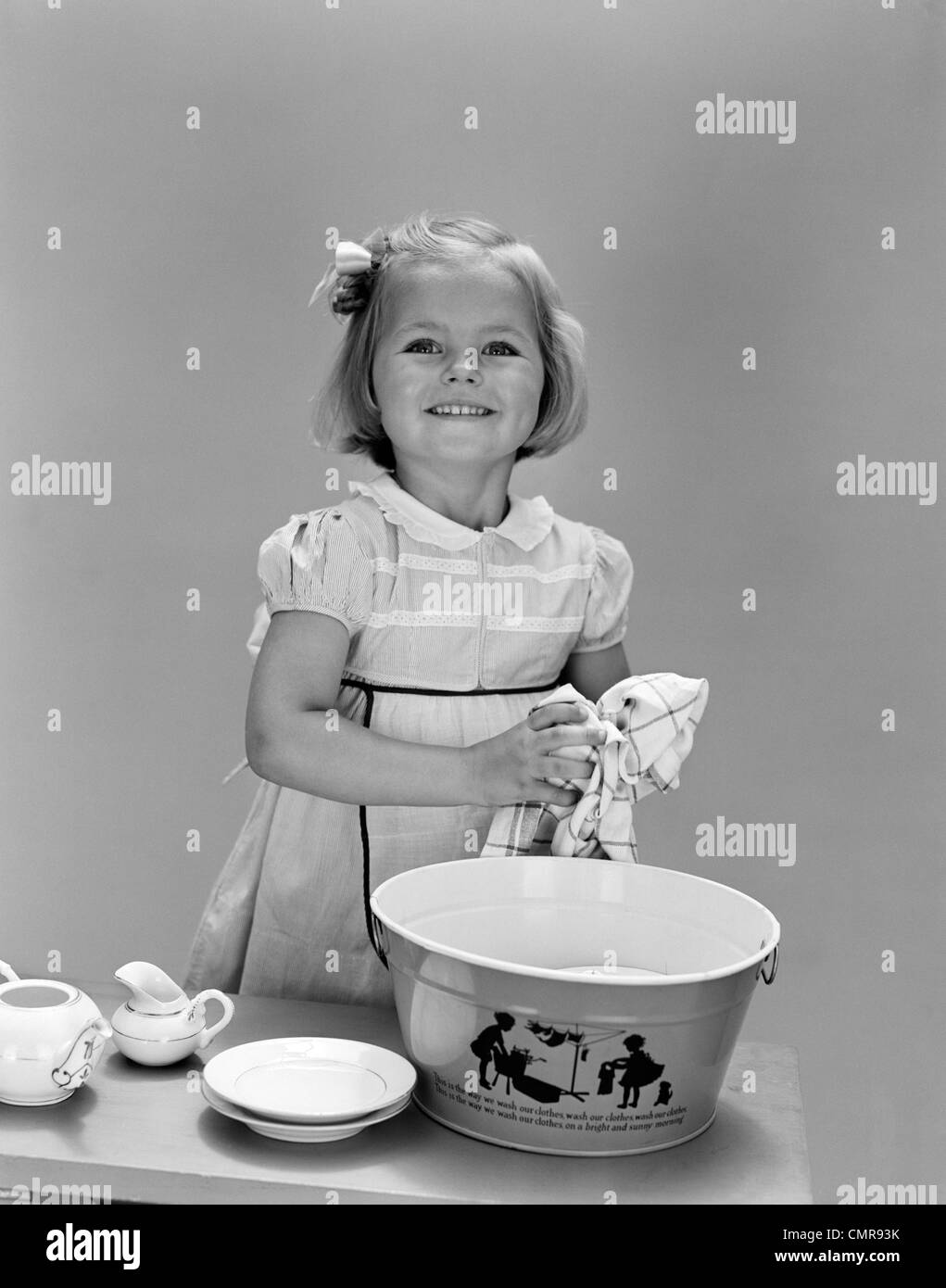 1940s bambino sorridente ragazza bionda lavaggio asciugatura stoviglie in TIN DISHPAN Foto Stock