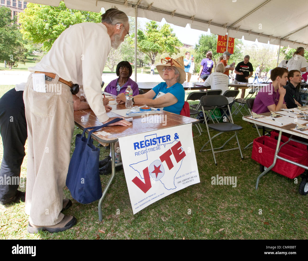 Lavoratore di sesso femminile che tende a una registrazione degli elettori tabella cercando di attirare potenziali elettori per iscriversi compresi i cittadini anziani Foto Stock