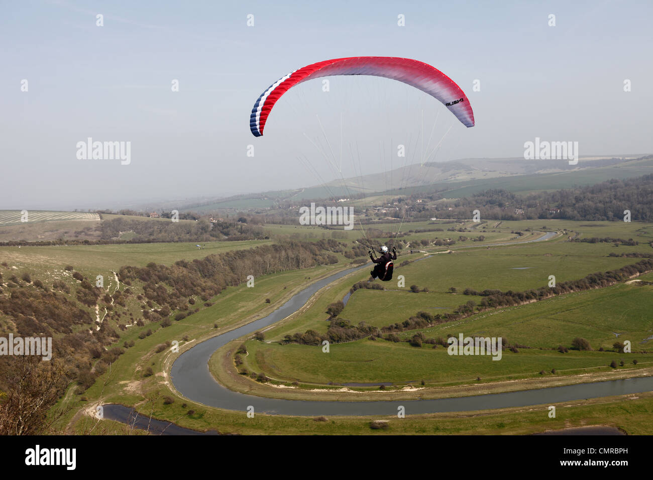 Parapendio vola da Rana Firle sopra la valle Cuckmere sul patrimonio del Sussex Costa, Inghilterra Foto Stock