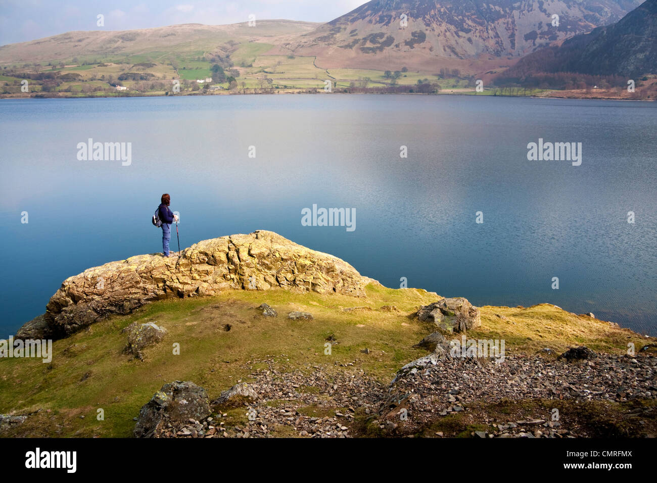 Un viandante sorgeva su un promontorio roccioso guardando Ennerdale acqua nel Lake District inglese. Foto Stock