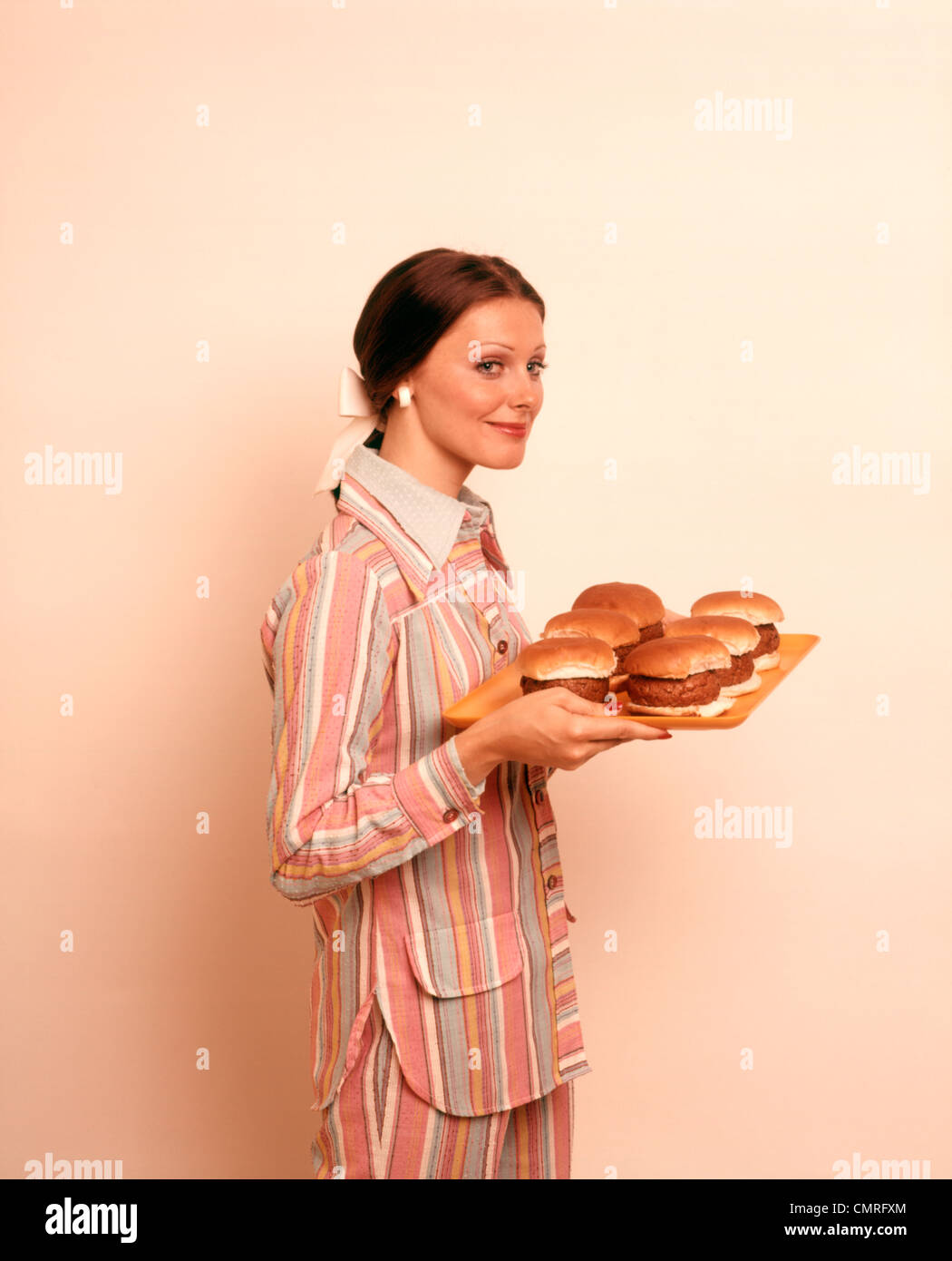 Anni Settanta donna casalinga tenendo il vassoio di hamburger Foto Stock