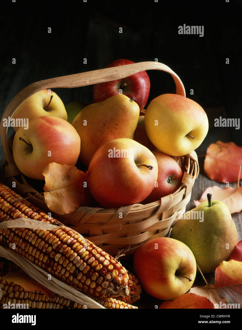Anni Novanta raccolto autunnale ancora vita mele pere in rovere spaccato cesto disposto con mais Indiano Foto Stock