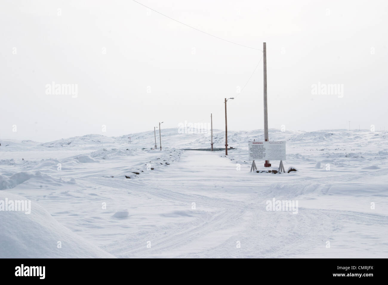 Segnale di avviso in lingua inglese e Inuktitut accanto a una coperta di neve dock, Iqaluit, Nunavut Foto Stock