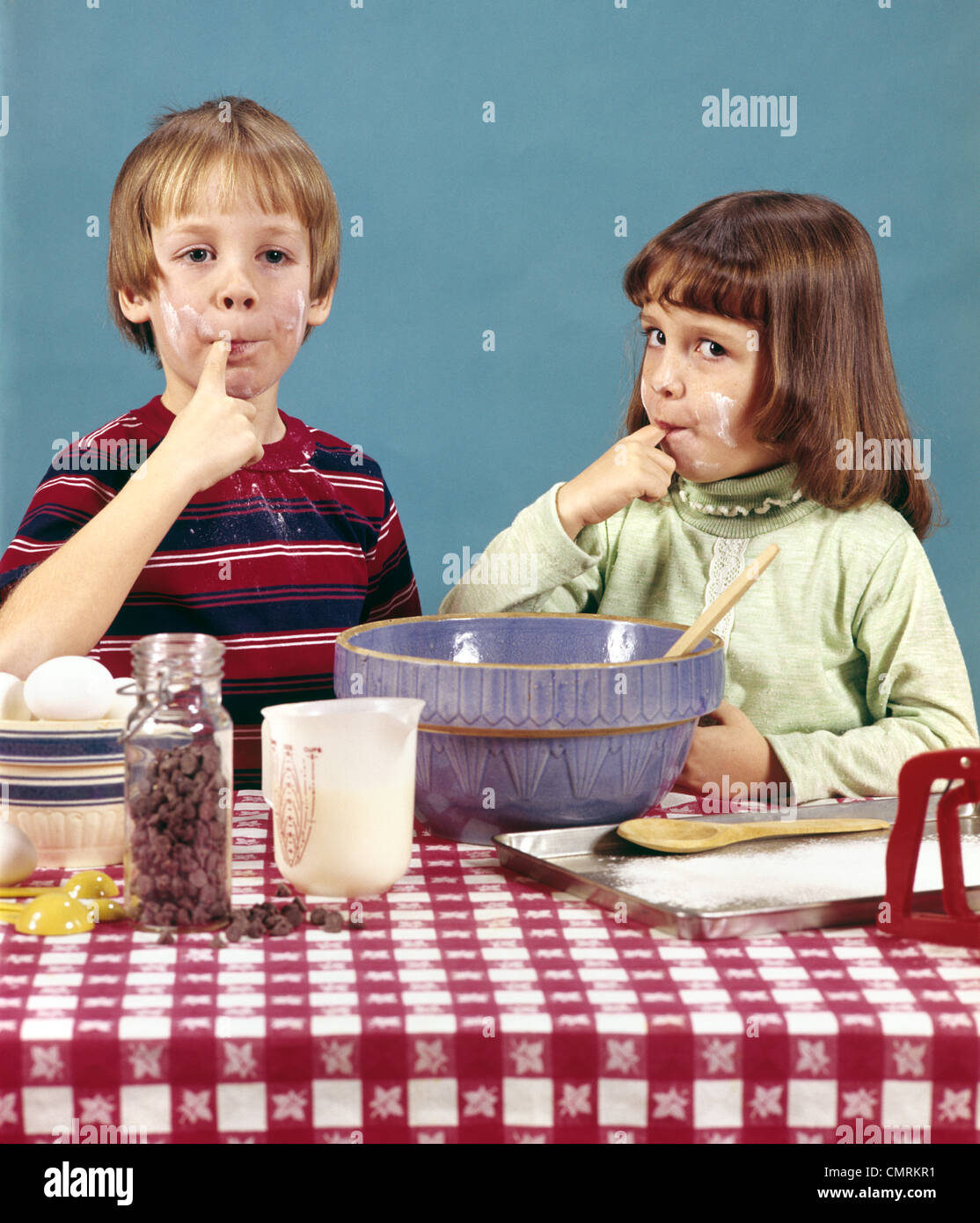 1970 anni settanta retrò ragazza ragazzo il fratello la sorella rendendo i cookie pastella di degustazione di cioccolato la cottura per la cottura Foto Stock
