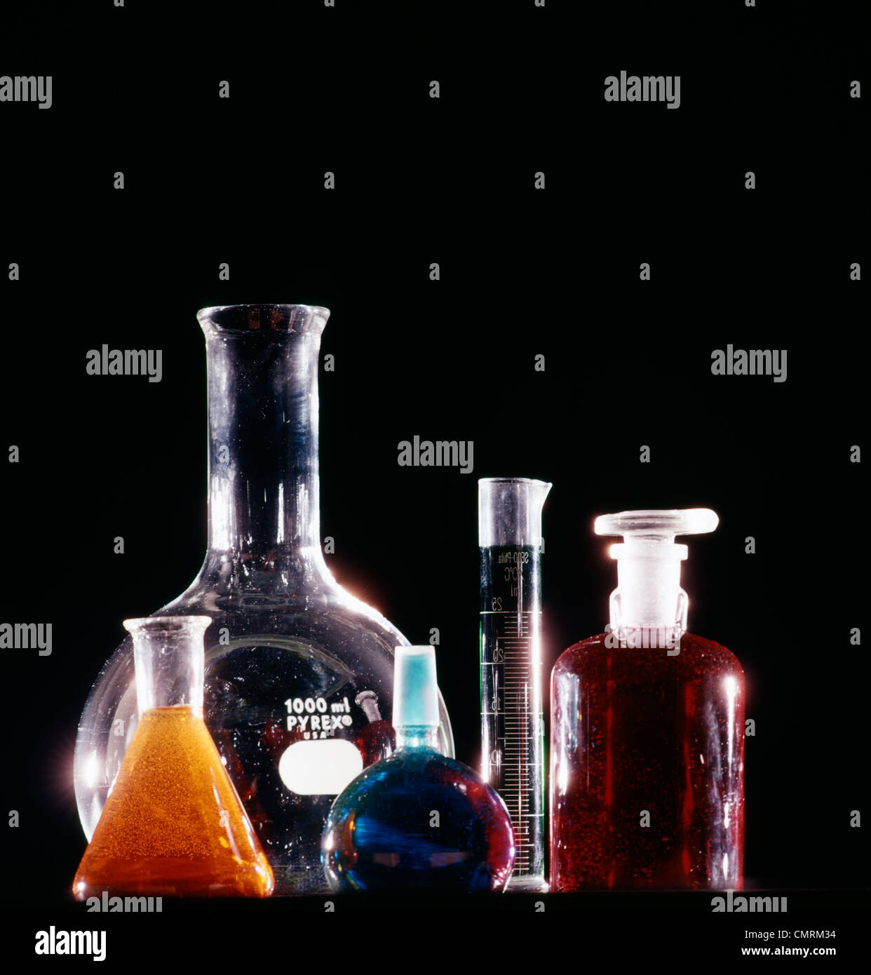 Vari formati di bottiglie di vetro di palloni e flaconi con liquidi colorati su sfondo nero Foto Stock