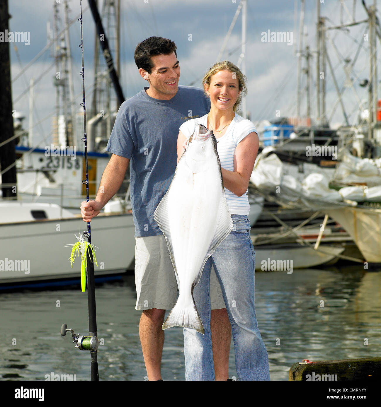 Donna che mantiene ippoglosso, ragazzo dietro di lei con una canna da pesca, Victoria, British Columbia Foto Stock