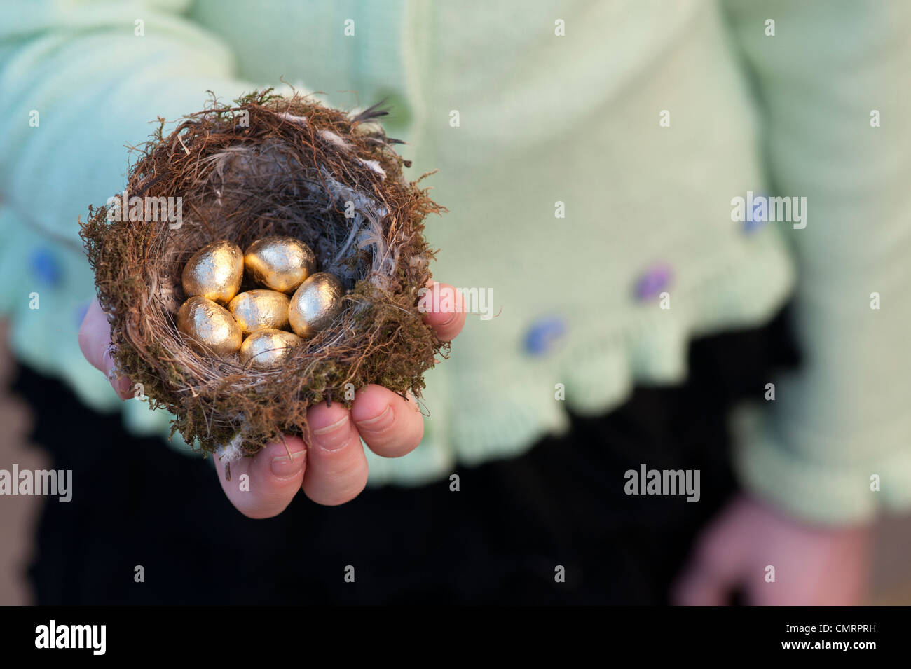 Ragazza con golden le uova in un nido di uccelli Foto Stock