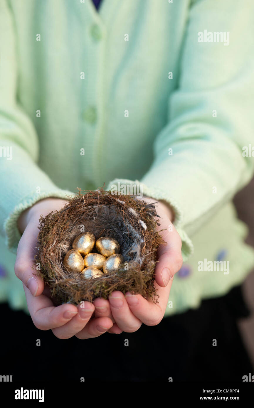 Ragazza con golden le uova in un nido di uccelli Foto Stock