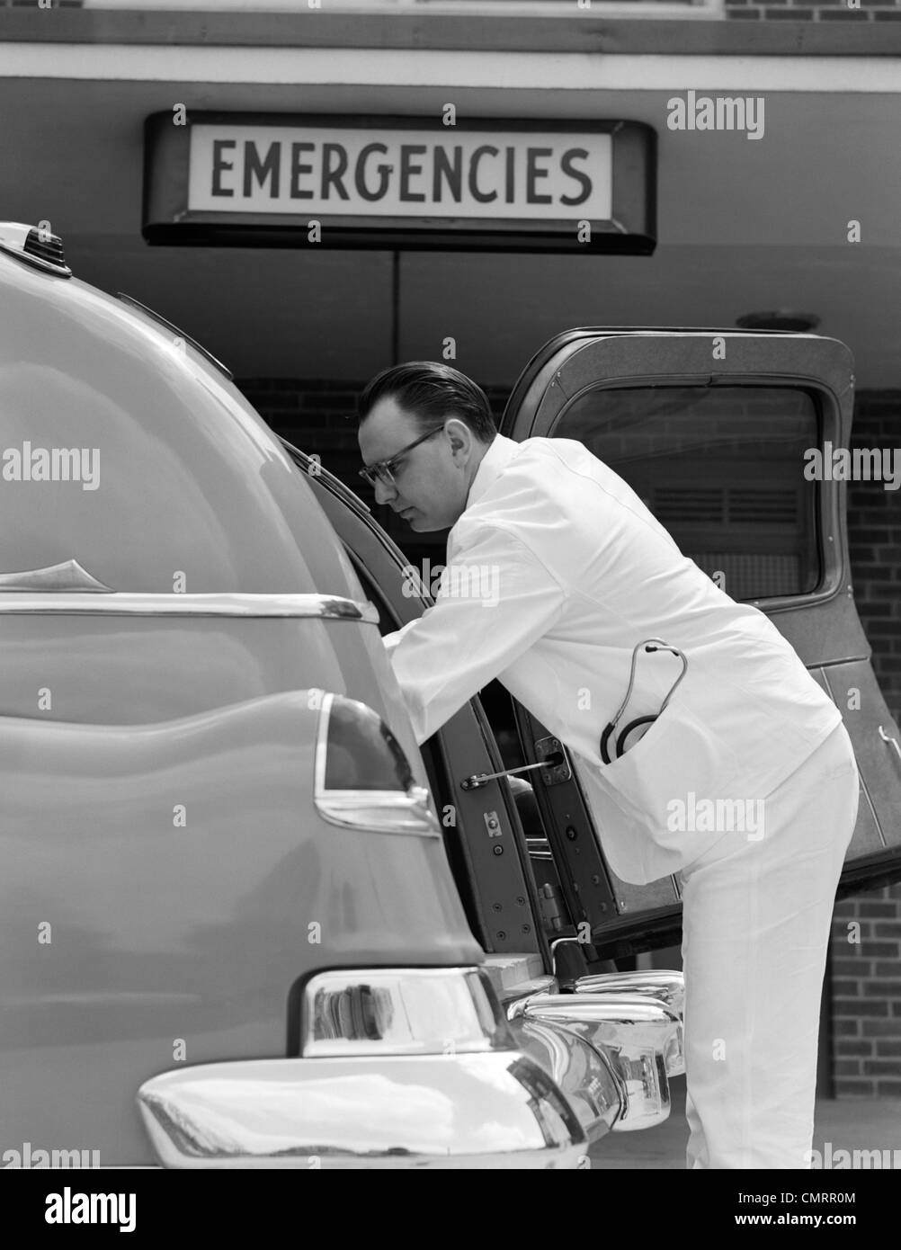 Degli anni Cinquanta vista laterale di autista di ambulanza in bianco uniforme con uno stetoscopio IN APERTURA DI TASCA POSTERIORE DI AMBULANZA PER TENERE FUORI DEL PAZIENTE Foto Stock