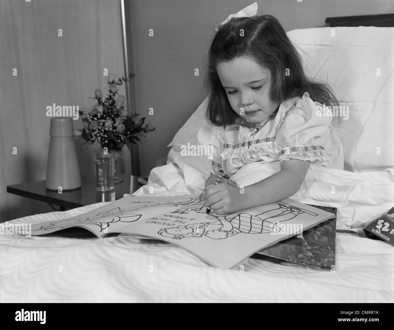Anni sessanta bambina paziente nel letto di ospedale iscritto nel libro da colorare Foto Stock