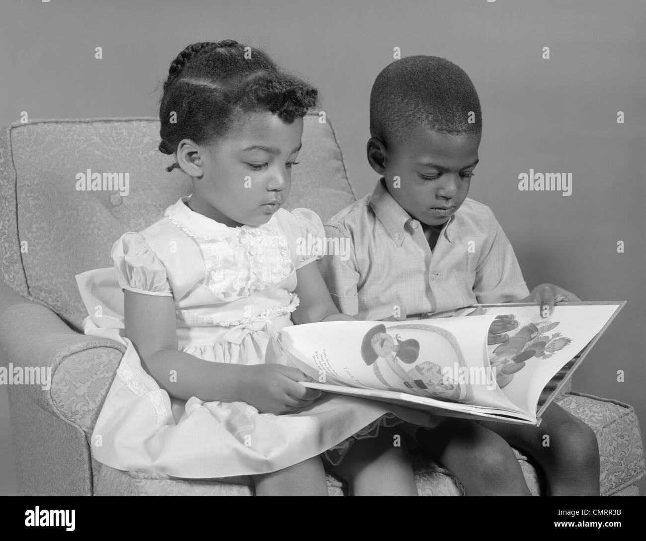 Anni sessanta AFRICAN-AMERICAN BOY E LETTURA DELLA RAGAZZA PRENOTA SEDUTA Foto Stock