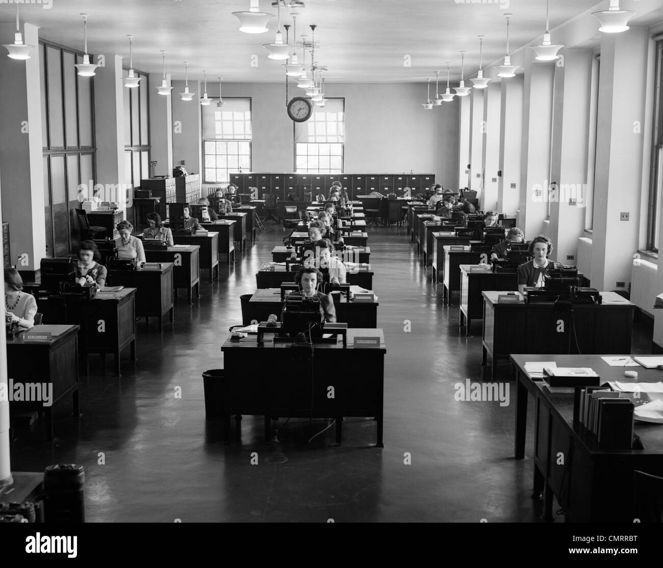 1930 UFFICIO CON RIGHE DI SEGRETARI FEMMINA FUNZIONANTE A SCRIVANIE CON MACCHINE DA SCRIVERE INDOOR Foto Stock