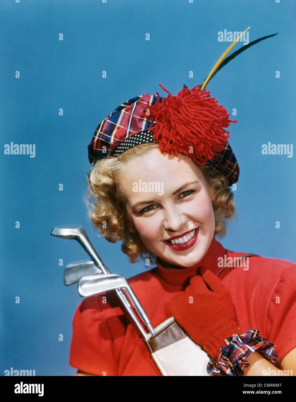 Negli anni quaranta anni cinquanta ritratto sorridente donna bionda che indossa PLAID TAM Guanti rossi holding club di golf guardando la fotocamera Foto Stock