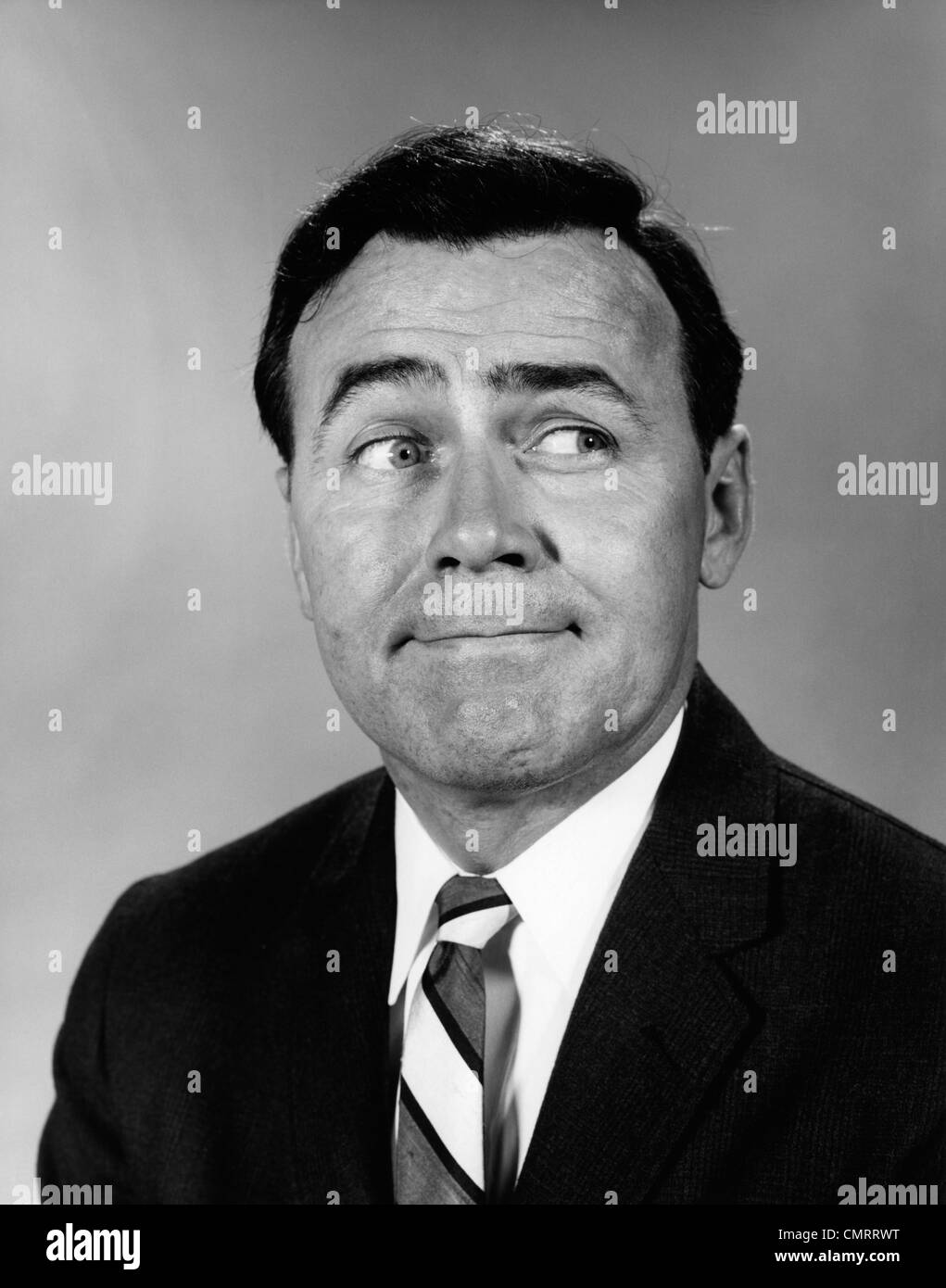 Anni sessanta imprenditore rendendo divertente faccia guardando al lato Foto Stock