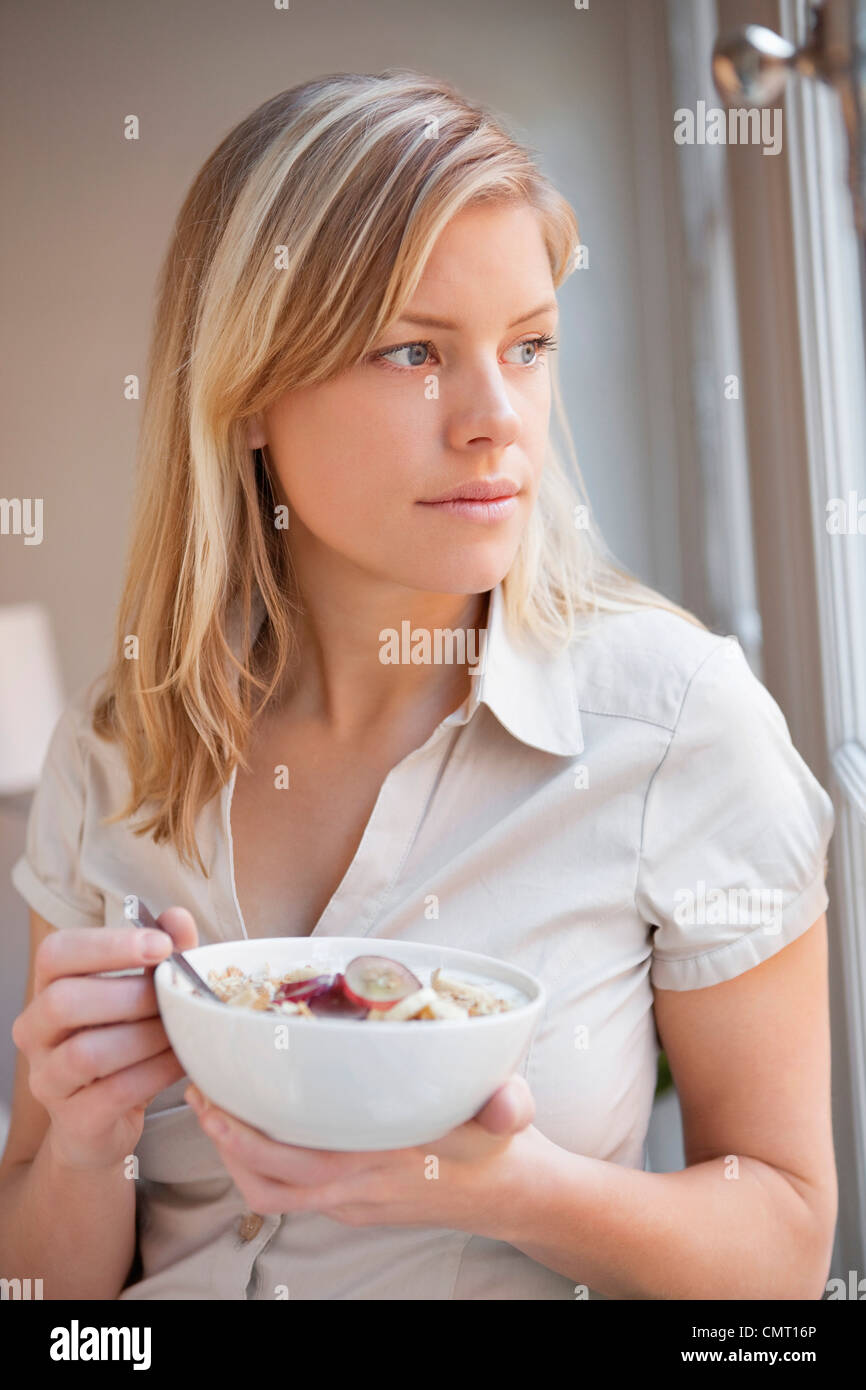 Donna di mangiare la prima colazione da finestra Foto Stock