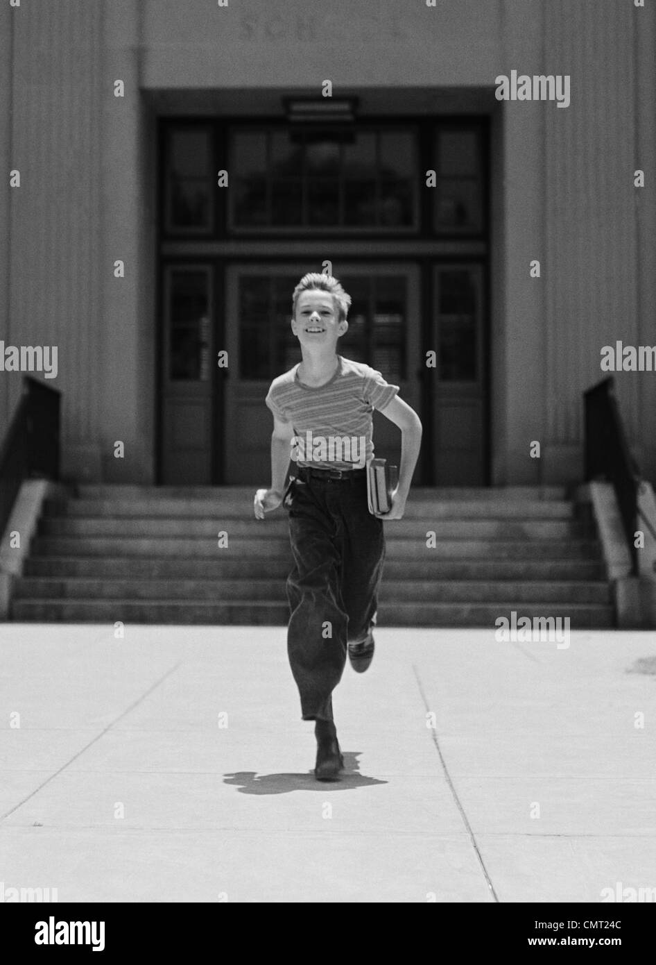 1930s 1940s BOY IN ESECUZIONE DALLA SCUOLA IL TRASPORTO DI LIBRI guardando la fotocamera Foto Stock