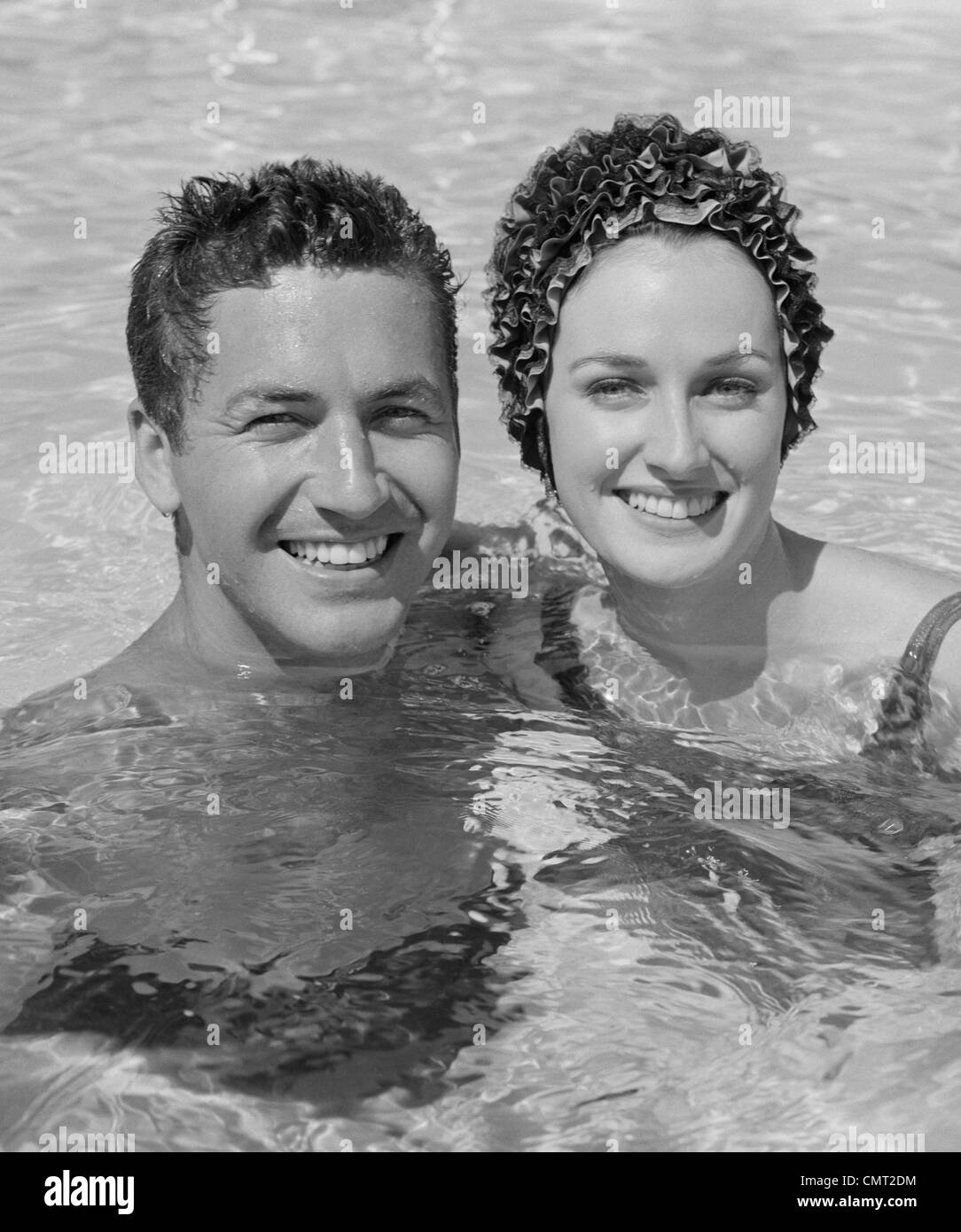 Anni sessanta sorridente GIOVANE DONNA UOMO IN PISCINA Foto Stock