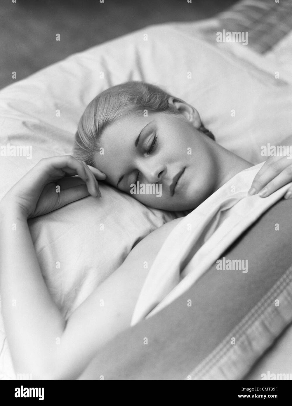 1930s SLEEPING DONNA BIONDA OCCHI CHIUSI testa in appoggio sul cuscino A LETTO Foto Stock