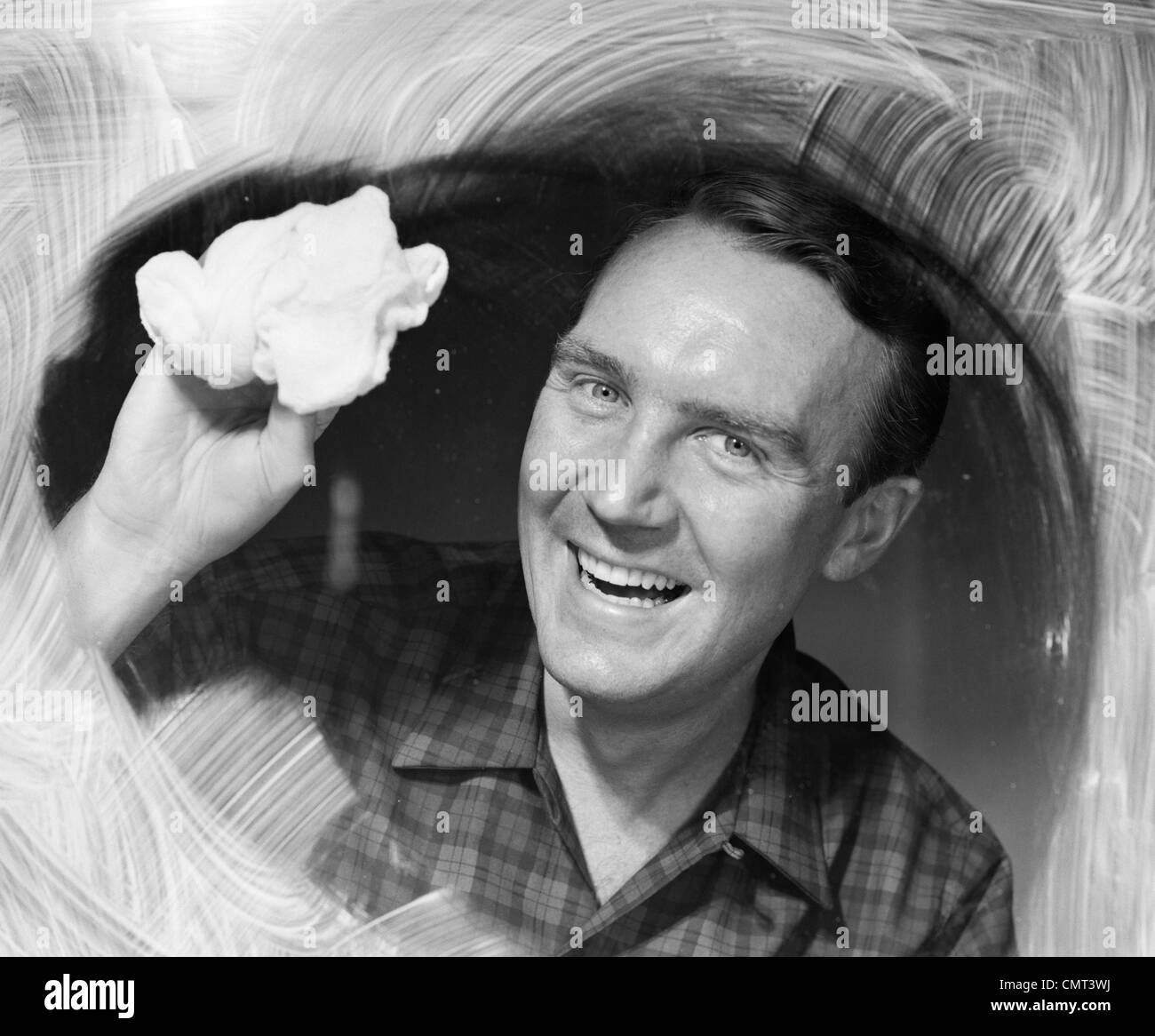 Anni Cinquanta anni sessanta uomo sorridente lavaggio vetro di finestra guardando la fotocamera Foto Stock