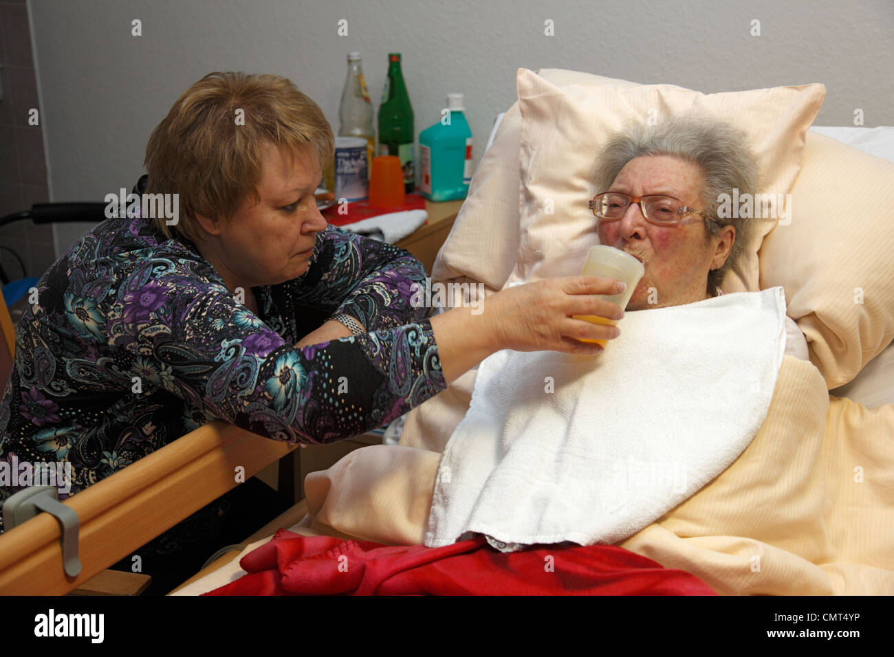 La gente, la vecchiaia, la casa di riposo, Altenzentrum der St. Clemens Hospitale in Sterkrade, donna anziana giace in un sickbed, di età compresa tra i 70 e 85 anni, un handicap fisico, la demenza malattia, infermiere detiene una coppa di alimentazione e aiuta a bere, di età compresa tra i 50 e i 60 anni, Waltraut Foto Stock