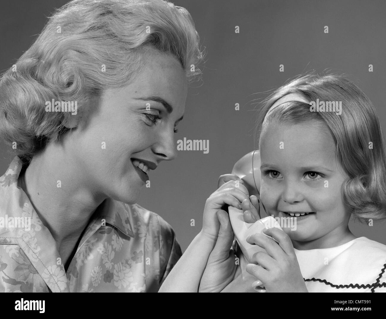 Anni Cinquanta anni sessanta madre guarda la figlia parlando al telefono Foto Stock