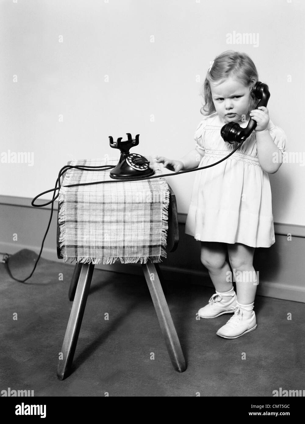 1930s 1940s misera accigliata bambina parlando sul vecchio nero MANOPOLA TELEFONO Foto Stock