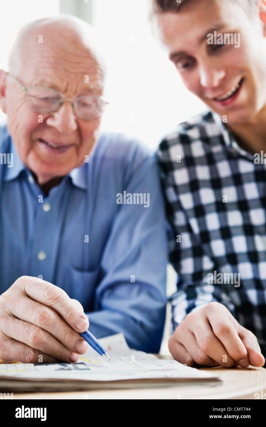 Guy e uomo anziano risolvendo il cruciverba Foto Stock