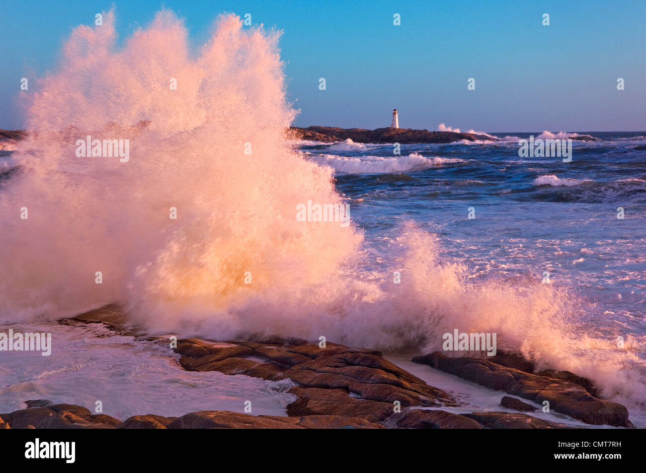I forti venti soffiano onde su rocce nella parte anteriore del faro di Peggy's Cove, Nova Scotia Foto Stock