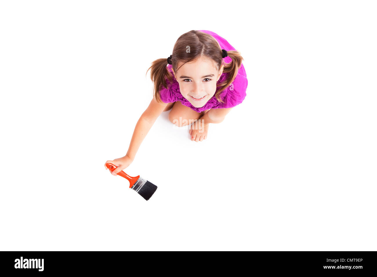 Vista dall'alto di un felice ragazza seduta sul pavimento tenendo un pennello Foto Stock