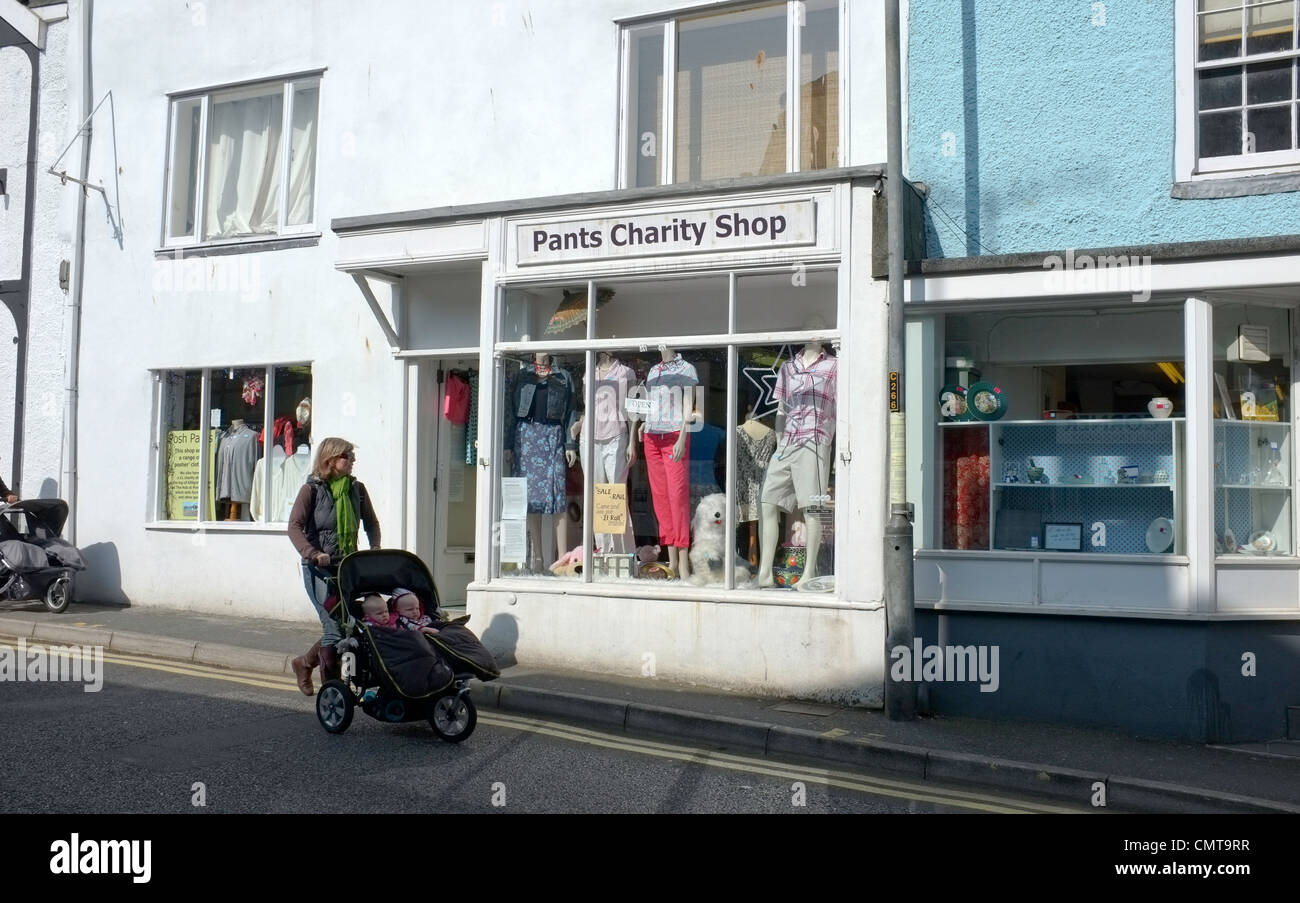 Una donna con un passeggino passa il pantalone carità shop in Falmouth, Regno Unito Foto Stock