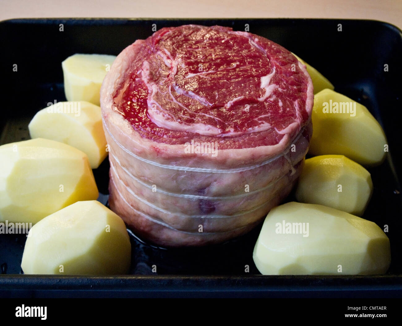 Una nervatura di manzo arrosto tagliato pronto per la cottura, con le patate in una pentola Foto Stock