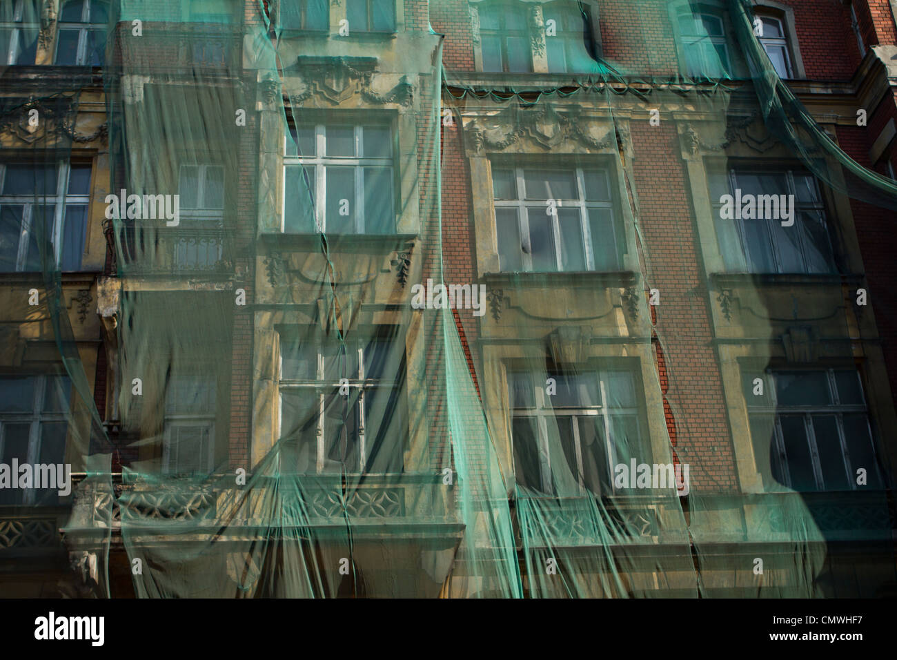 Facciata di un edificio di decadimento coperto dalla protezione maglia verde contro la caduta di pezzi di intonaco. Katowice in Polonia. Foto Stock