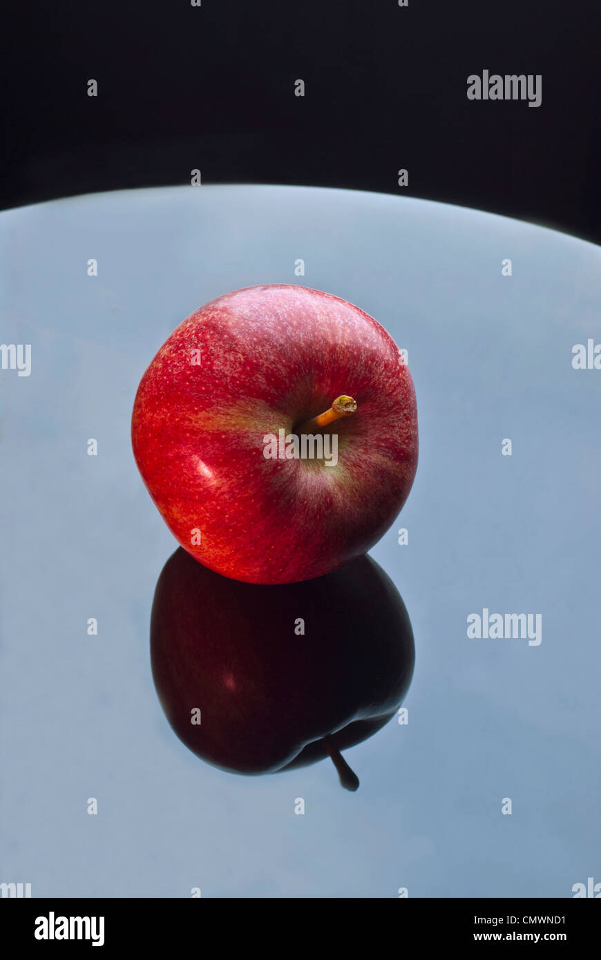 Unico rosso fresco Apple su un tavolo di vetro con la riflessione non morde preso fuori di esso Foto Stock