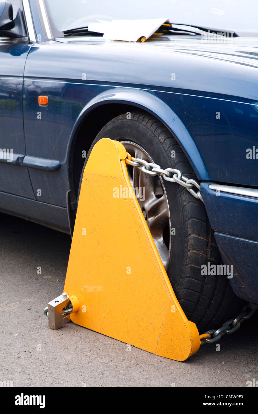Primo piano di un giallo a morsetto di bloccaggio di ruota fissato alla ruota di un automobile Foto Stock