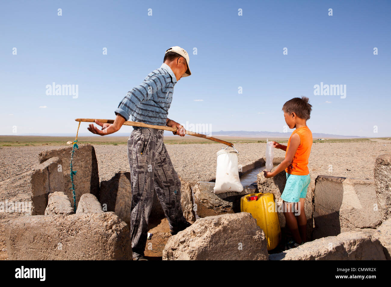 Padre e figlio bail il bene acqua nel deserto dei Gobi, Mongolia Foto Stock