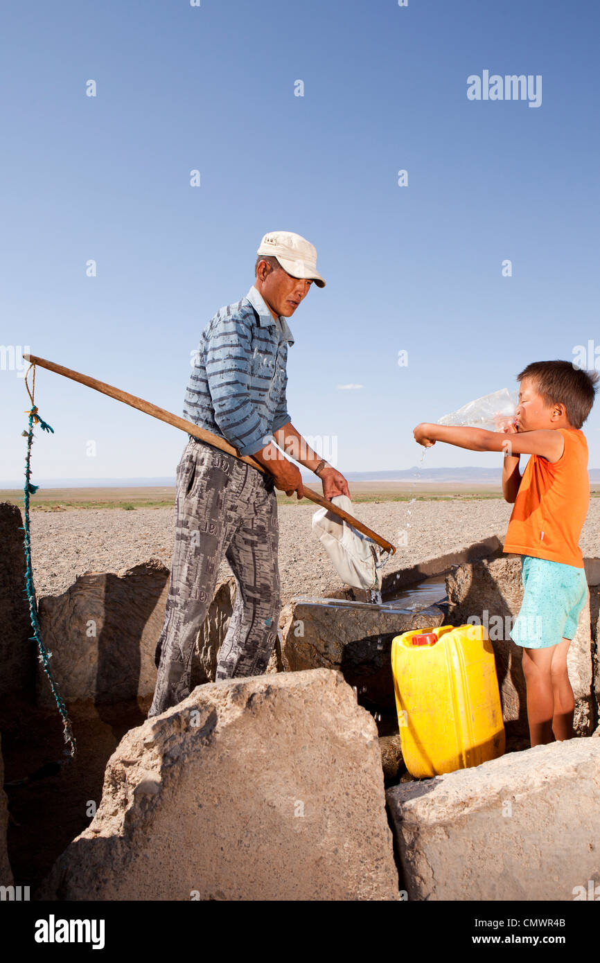 Padre e figlio bail il bene acqua nel deserto dei Gobi, Mongolia Foto Stock