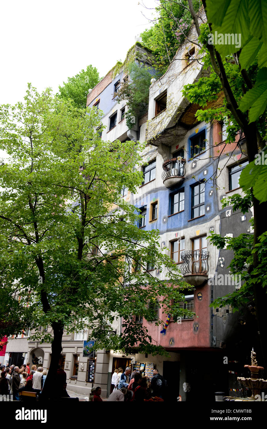 Verdi alberi che circondano la facciata della Friedensreich Hundertwasser edificio. Foto Stock