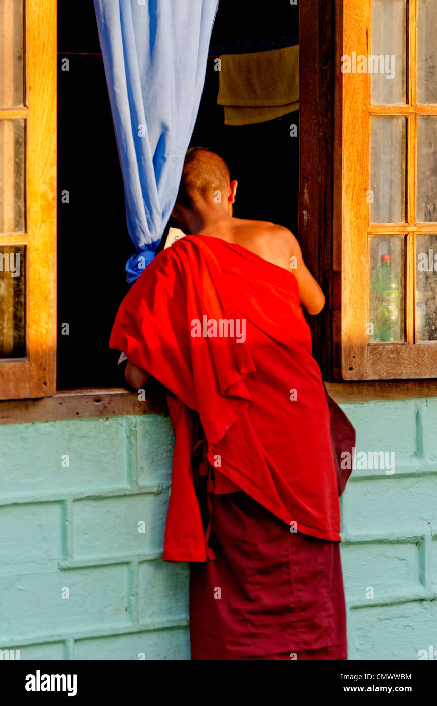 Giovane Monaco cercando nella finestra, Nyaungshwe, Myanmar Foto Stock