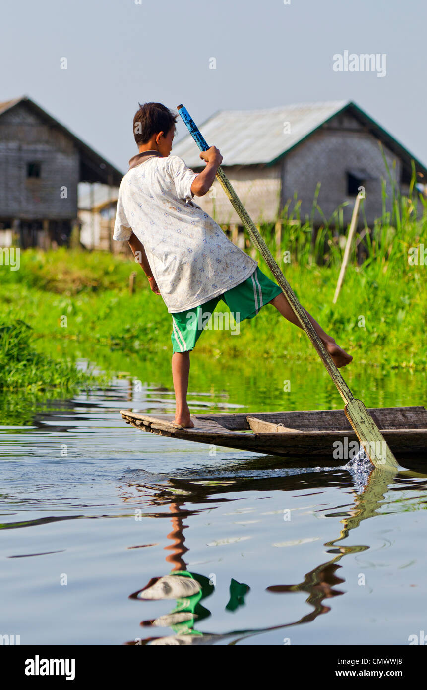 Giovane ragazzo in barca a remi in modo tradizionale, Lago Inle, Myanmar Foto Stock