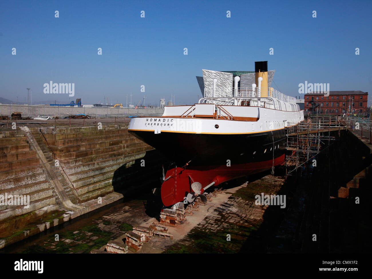 La nave nomadi si siede nel bacino di carenaggio con il Titanic Visitor Centre in background in Belfast, Irlanda del Nord Foto Stock