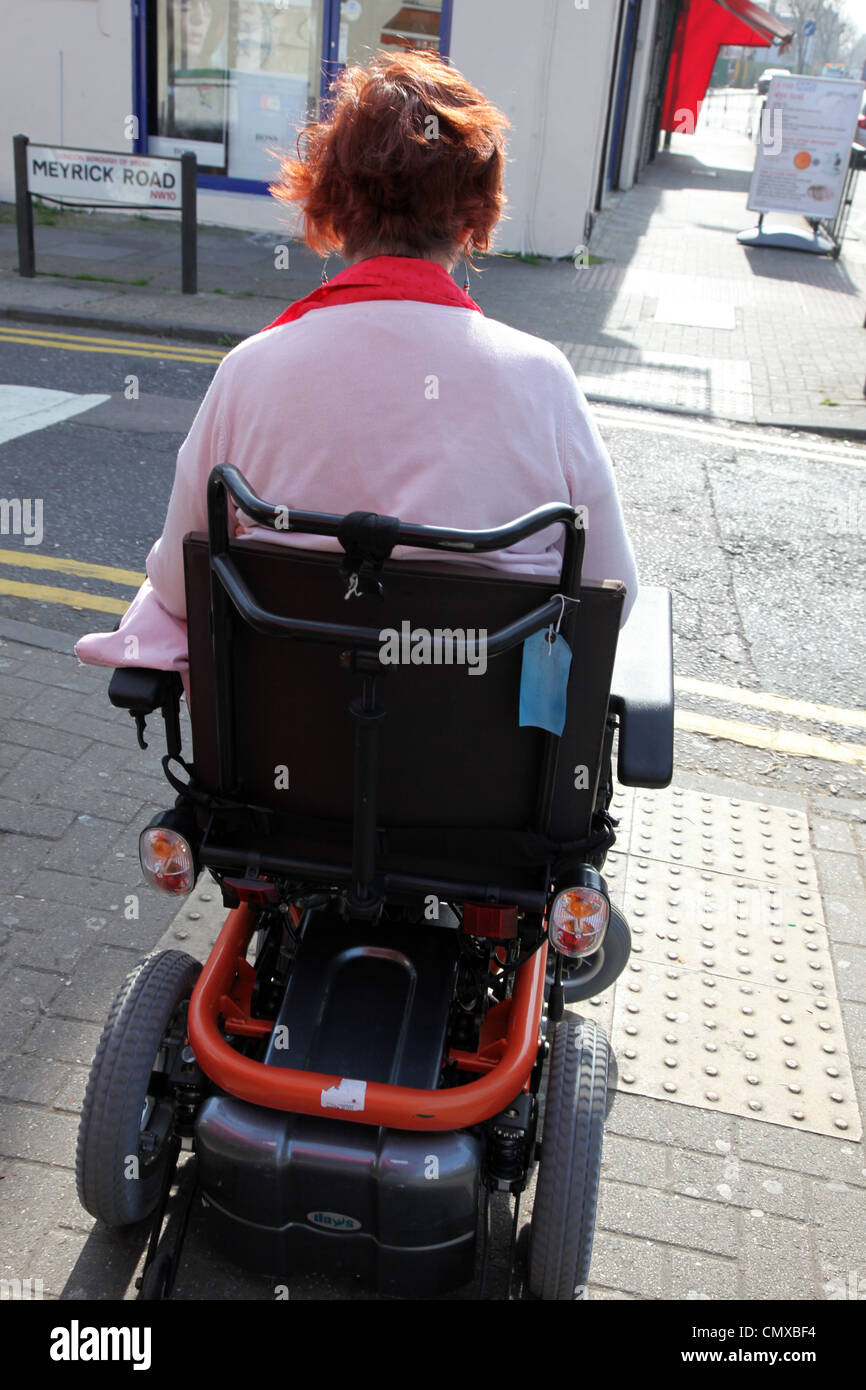 Sedia a rotelle la guida utente al di sopra di predisposte pavimentazione in pendenza Foto Stock