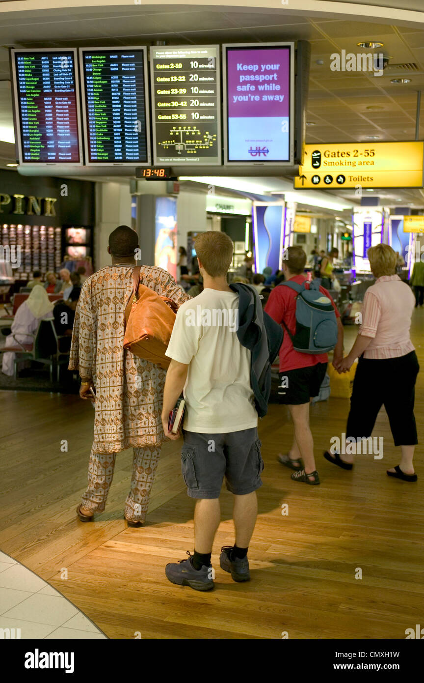 Passeggeri controllare le informazioni visualizzate in Aeroporto, London, Regno Unito Foto Stock