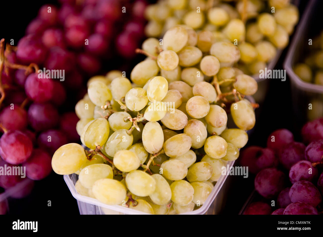 Uva verde dominante in un'immagine circondata da uve rosse sui fianchi. Foto Stock