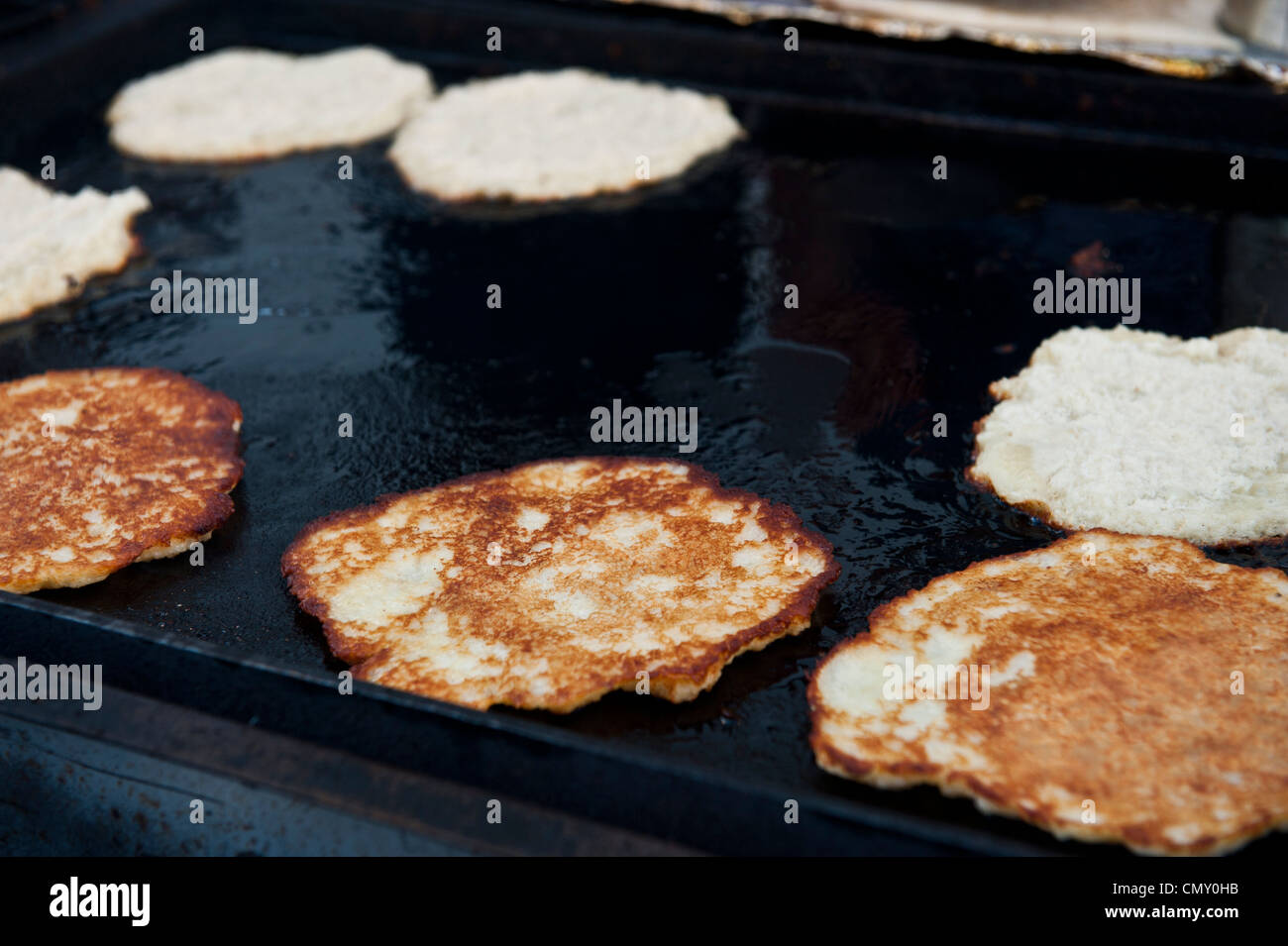 Alcuni latkes in attesa di essere girata per cuocere alla perfezione come le altre immagini nitide, latkes cotte alla griglia. Foto Stock