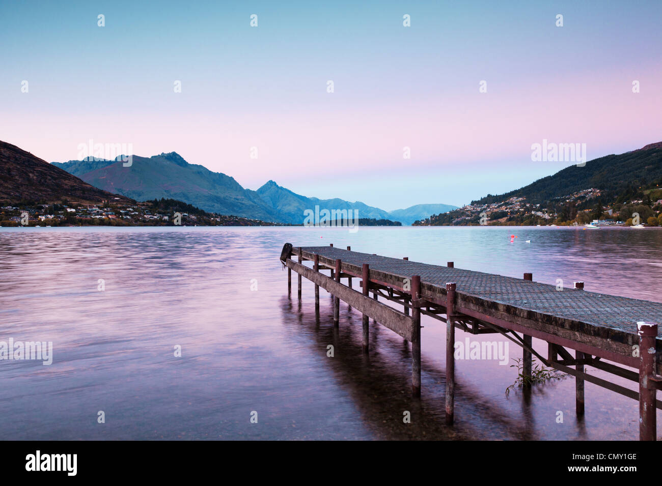 Un vecchio molo sulle rive del lago Wakatipu, Queenstown, Otago, Nuova Zelanda, e Queenstown in distanza. Foto Stock