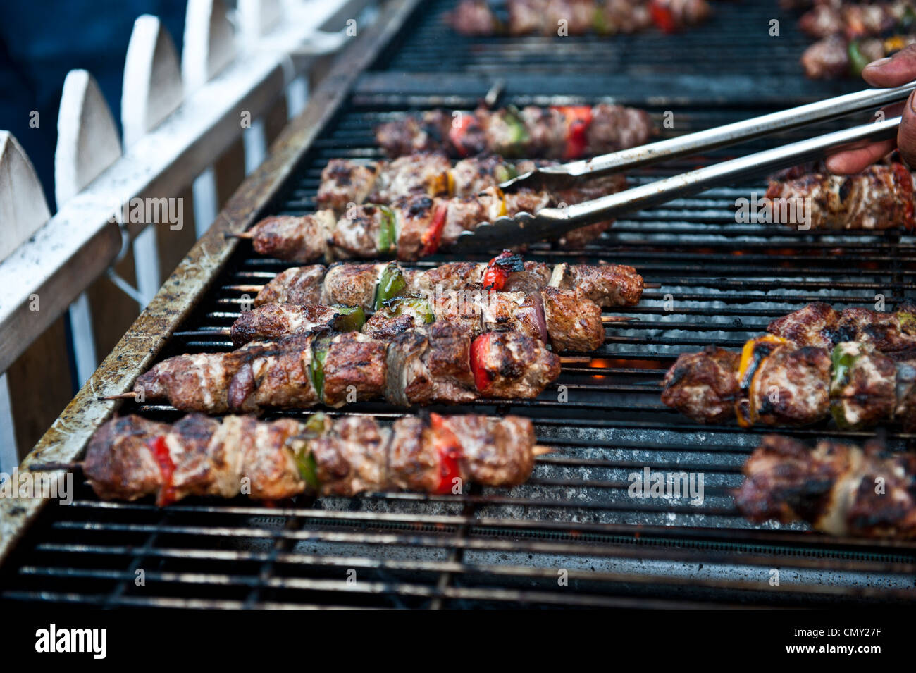 Shish spiedini alla brace sulla griglia dietro un recinto di bianco. Foto Stock