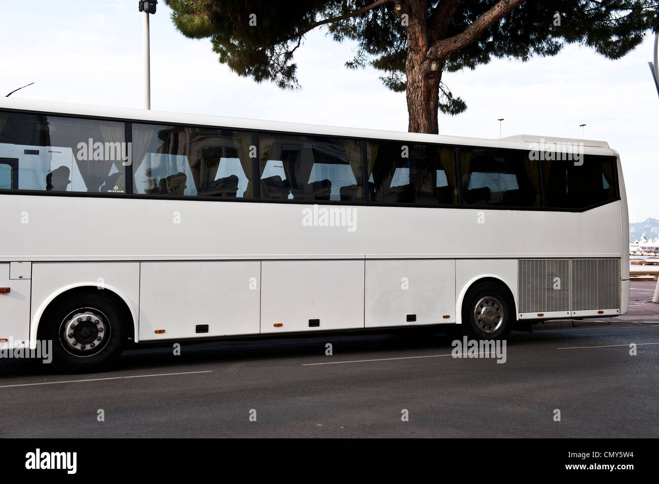 Il lato di un bus bianco guidando lungo la strada in una giornata di sole. Foto Stock