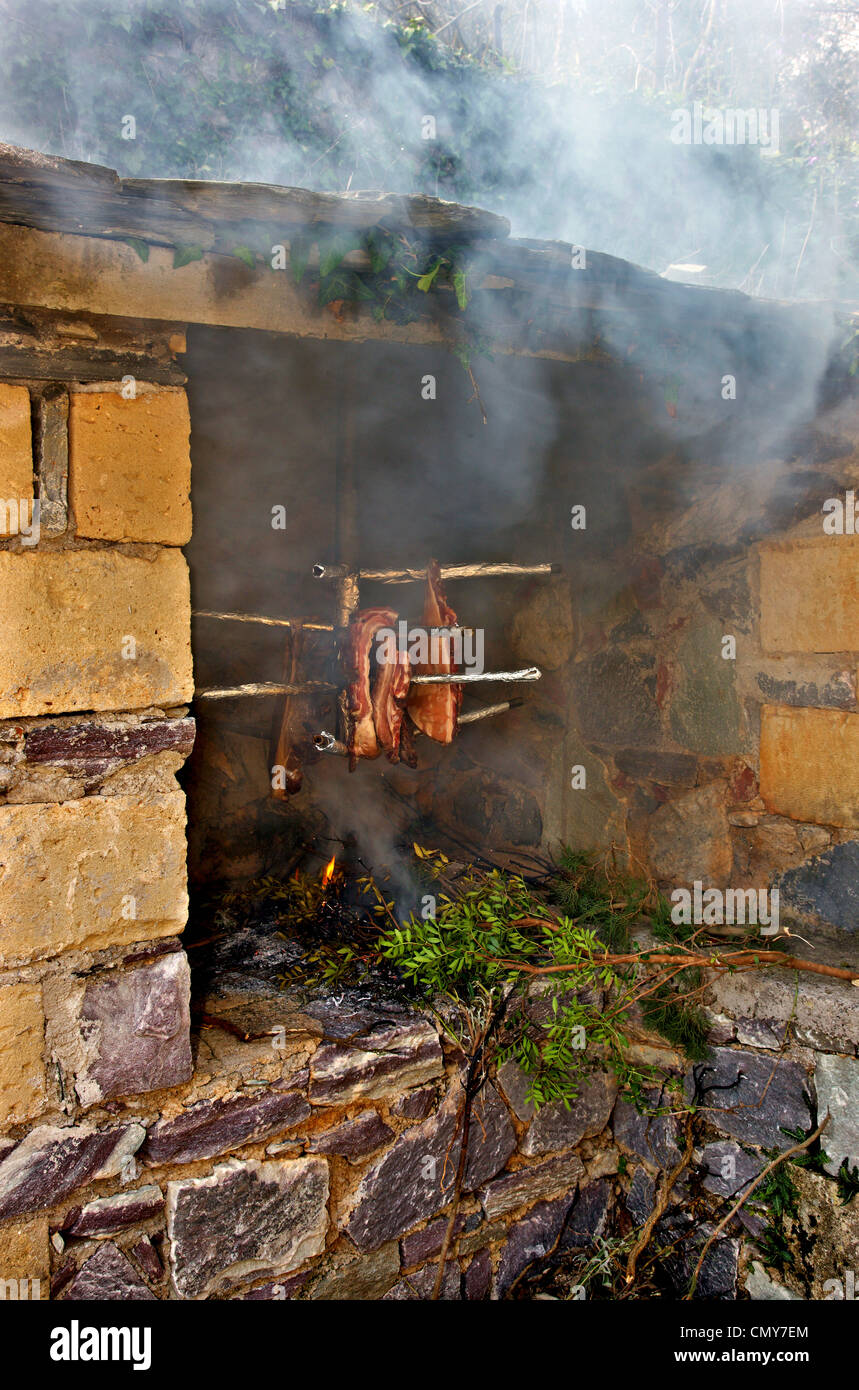 Preparazione di 'syglino' (noto anche come "pasto'=affumicato di maiale) una famosa prelibatezza locale e salsicce in mani, Messinia Grecia. Foto Stock
